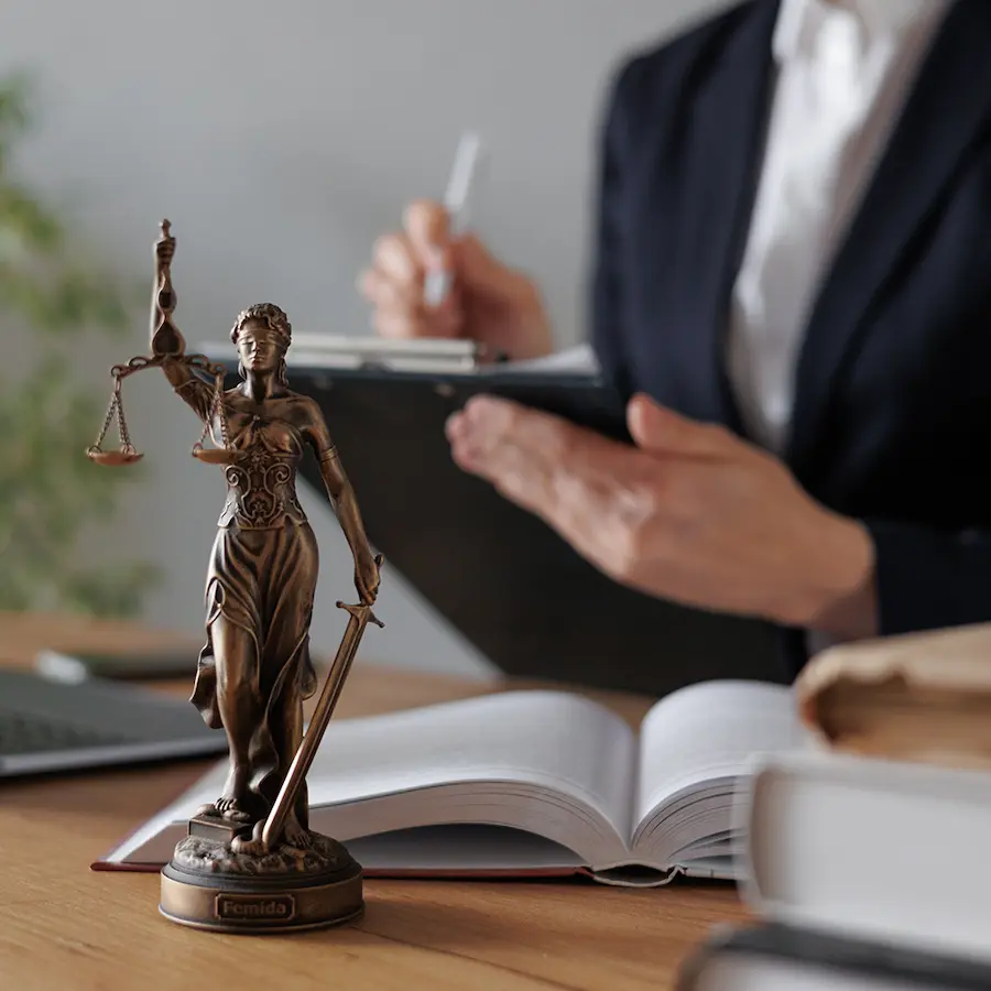 Estátua da Justiça e Advogada com tablet trabalhando na mesa